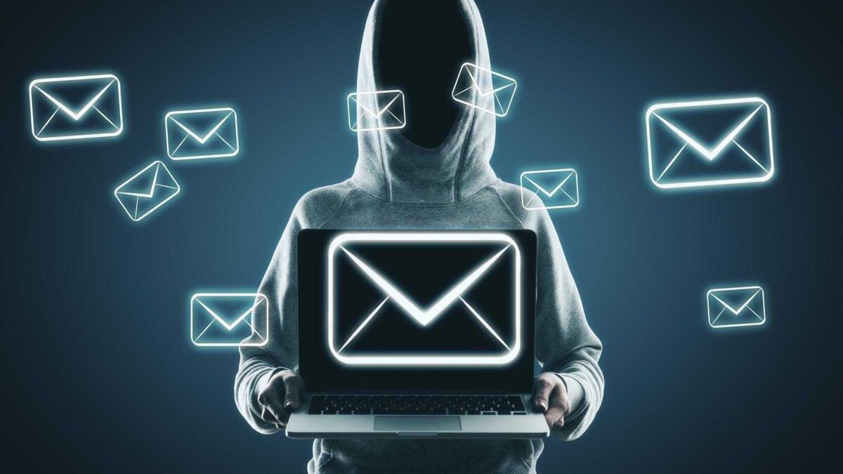 Хакер в hoodie держит ноутбук с иконками электронной почты