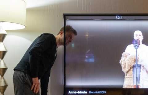 Человек смотрит на прозрачный OLED телевизор LG на стене