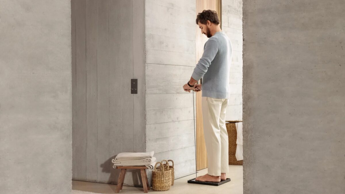 Человек взвешивается на умных весах Withings Body Scan 2 в ванной комнате